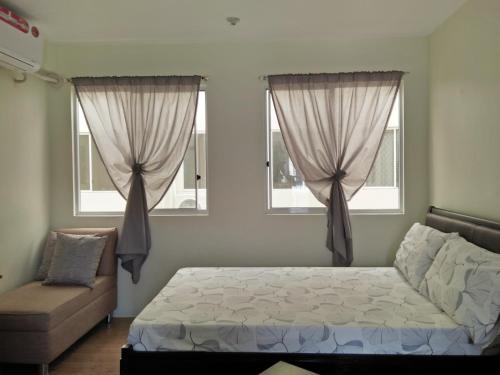 Un dormitorio con una cama y dos ventanas. en Stay at Sanremo Oasis Cebu, en Cebú