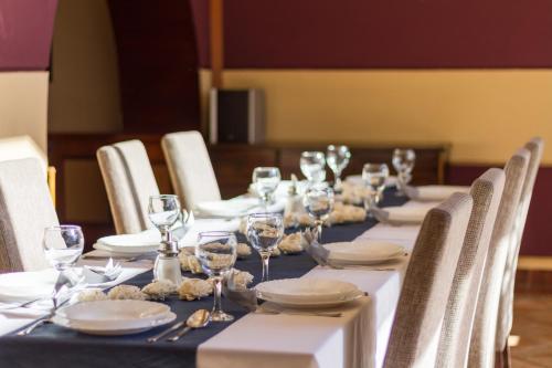 a long table with plates and wine glasses on it at Hangya Panzió és Étterem in Csepreg
