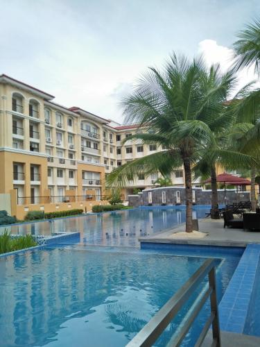 a large swimming pool with palm trees in front of a building at Stay at Sanremo Oasis Cebu in Cebu City
