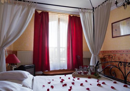 a bedroom with red curtains and roses on a bed at Hangya Panzió és Étterem in Csepreg