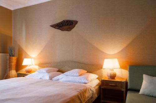 a bedroom with a bed with two lamps and a rock on the wall at Hangya Panzió és Étterem in Csepreg