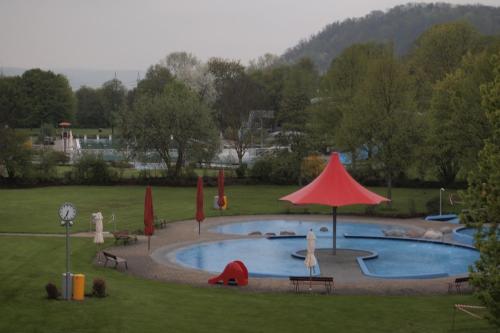 a large swimming pool with a red umbrella in a park at Hotel am Bad in Tübingen