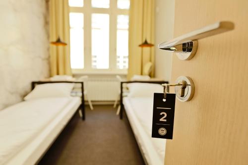 a room with two beds and a door with a sign on it at Sleep in Hostel & Apartments Stary Rynek in Poznań