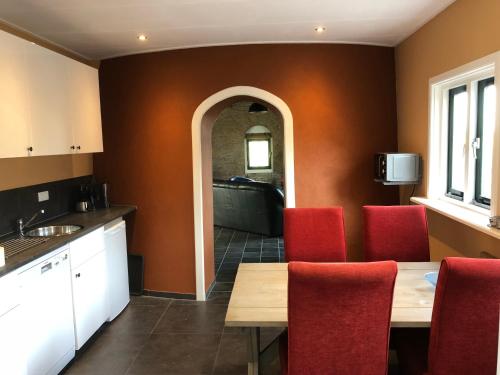 a kitchen with a wooden table and red chairs at De goede verwachting in Kamperland
