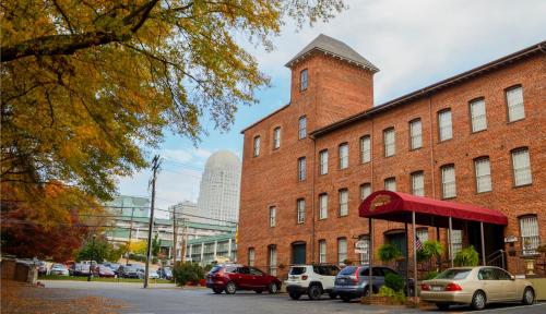 un edificio de ladrillo con coches aparcados en un aparcamiento en The Historic Brookstown Inn, Trademark Collection by Wyndham, en Winston-Salem