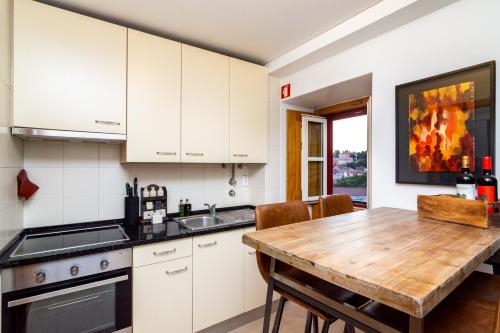 a kitchen with white cabinets and a wooden table at The Explorers Home - Sunny Stylish Family-Friendly Apartment in Lisbon