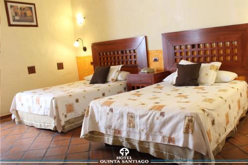 a hotel room with two beds with white sheets at Hotel Quinta Santiago in Querétaro