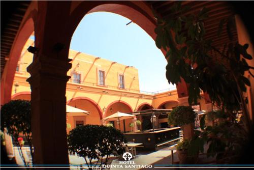 a building with an archway with trees in a courtyard at Hotel Quinta Santiago in Querétaro