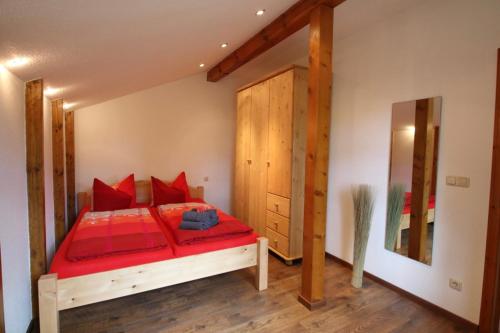 SaalにあるFerienwohnung Baumannの赤いベッドと木製のドアが備わるベッドルーム1室が備わります。