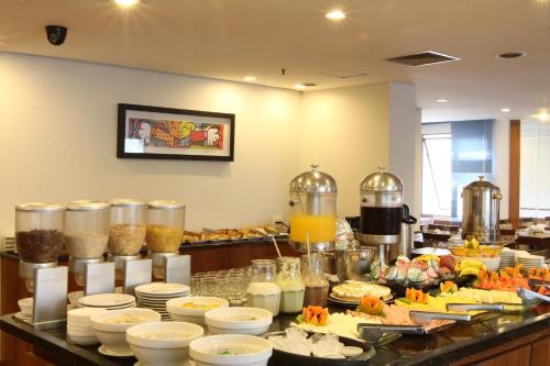 a buffet line with plates and bowls of food at Travel Inn Hotels Ibirapuera in Sao Paulo