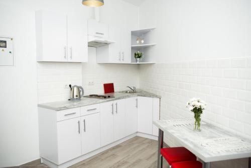 a kitchen with white cabinets and a table with a vase of flowers at Deluxe Apartment in old city center in Lviv