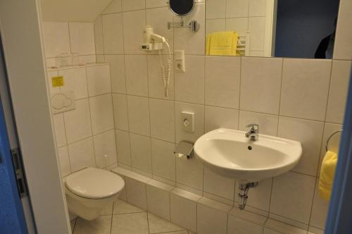 a white bathroom with a toilet and a sink at Hotel Bürgerhof in Homburg