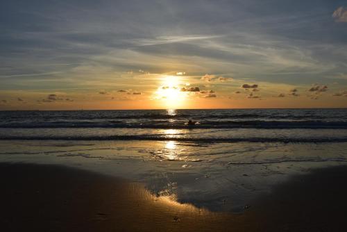 a person riding a wave in the ocean at sunset at Chalet Oester 167 in Ballum