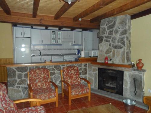 a living room with two chairs and a stone fireplace at La Puente 10 de Gredos in Hoyos del Espino