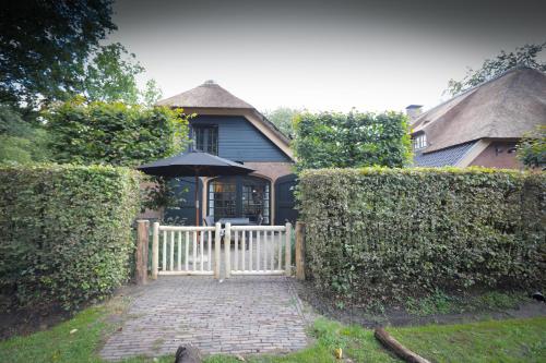 a house with a white fence and an umbrella at Lindenhof in Garderen