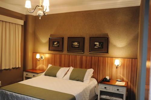 a bedroom with a bed with two night stands and two pictures on the wall at Hotel Kehdi Plaza in Barretos