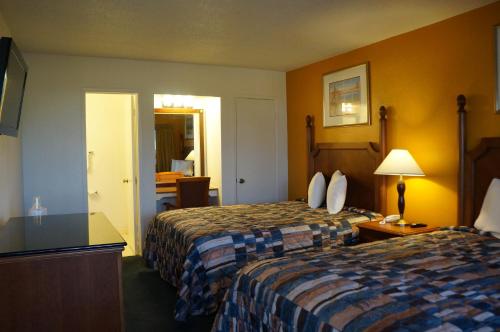 a hotel room with two beds and a desk at Classic Inn in Red Bluff