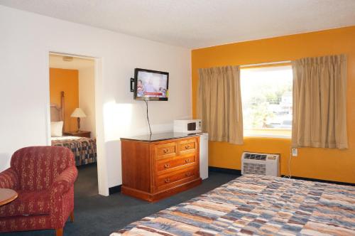 a hotel room with a bed and a chair and a window at Classic Inn in Red Bluff