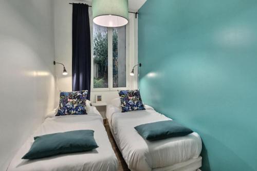 deux lits dans une chambre avec une fenêtre dans l'établissement Les Appartements d'Edmond Sylvabelle, à Marseille