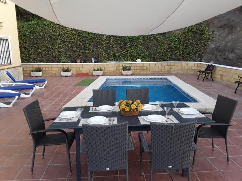 a dining table and chairs next to a swimming pool at Villa Paloma in Árchez