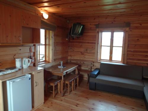 a kitchen with a table and a couch in a cabin at Country Houses Vidų Sodyba in Utena