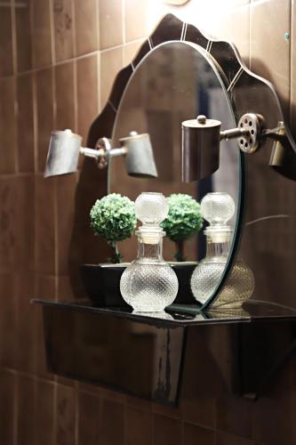 a shelf with two glass bottles and flowers in front of a mirror at Maria Court 2, Apt 32 in Larnaca