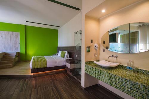 ein Schlafzimmer mit einer grünen Wand mit einem Bett und einem Waschbecken in der Unterkunft Hotel y Villas Natura in Mexiko-Stadt