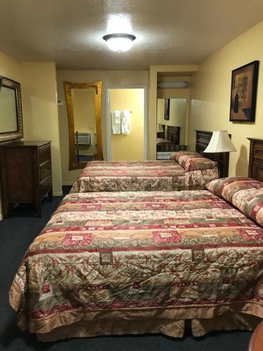 a hotel room with two beds and a mirror at Hacienda Motel in Escondido