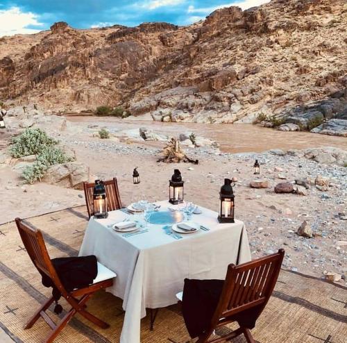 a dinner table with chairs and lights in the desert at Amoudou Lodge Camp in Tissint