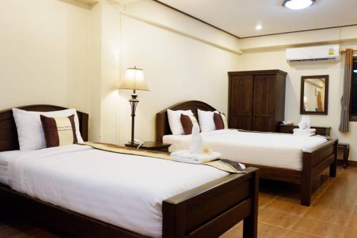 a hotel room with two beds and a lamp at NanBaanKhun Hotel in Nan