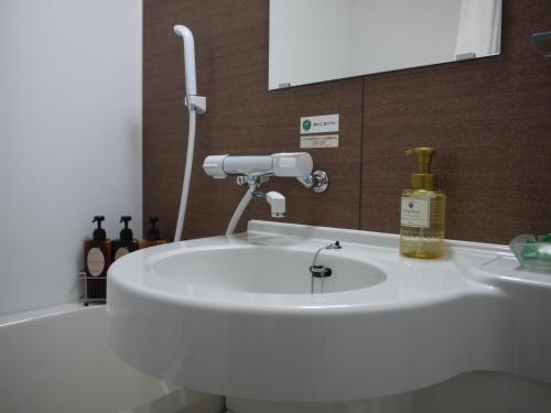 Hotel Route-Inn Ishioka في Ishioka: بالوعة بيضاء في الحمام مع مرآة