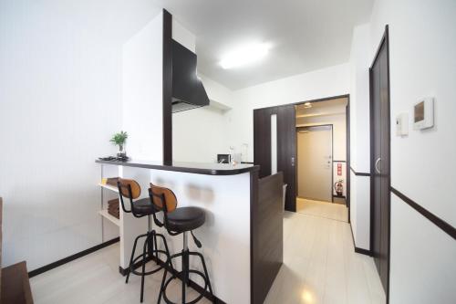 uma cozinha com um balcão e bancos num quarto em EX Itoman Apartment 202 em Itoman