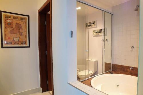 uma casa de banho com uma banheira e um WC com uma cabina de duche em vidro. em Residencial Yacamim B39 em Ilhabela