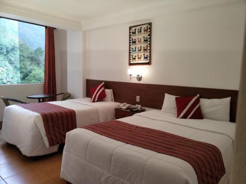 a hotel room with two beds and a window at Viandina Machupicchu in Machu Picchu