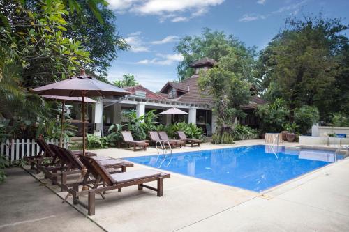 uma piscina com cadeiras e um guarda-sol ao lado de uma casa em Eurasia Chiang Mai Hotel em Chiang Mai
