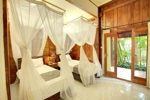 a bedroom with two beds with white drapes at Bali Dream Resort Ubud in Ubud