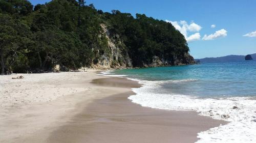 a sandy beach with the ocean and a mountain at Buena Vista Apartment in Marahau