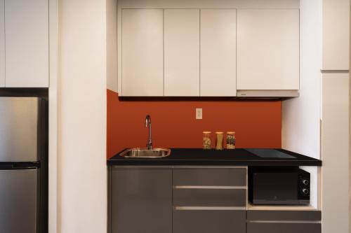 a kitchen with white cabinets and a sink and a microwave at Citadines Central Binh Duong in Thuan An