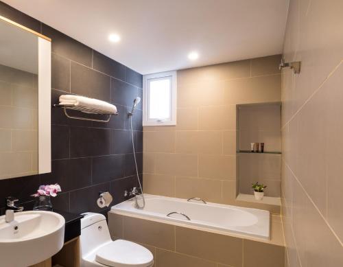 a bathroom with a sink and a tub and a toilet at Citadines Central Binh Duong in Thuan An
