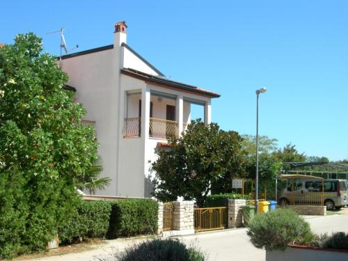 una casa blanca con una valla y árboles en Apartments Nadija, en Rovinj