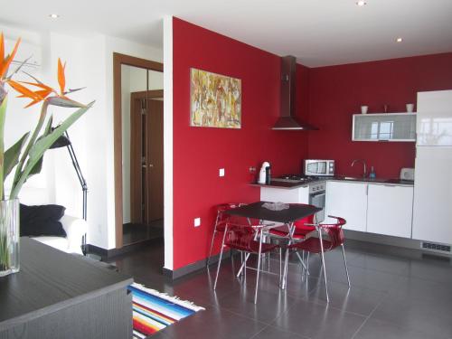 a kitchen with red walls and a table and chairs at Silver Coast Vacation - Your Unique Inn in Lourinhã