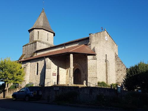 a church with a tower and a car parked in front at Auberge de la vallee de la gorre in Saint-Auvent