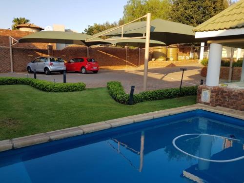 uma piscina azul em frente a um parque de estacionamento em Jolani Guest House em Welkom