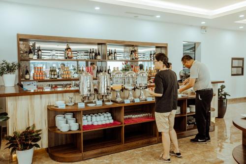 two people standing at a counter in a coffee shop at Sun Bay Tuan Chau Hotel in Ha Long