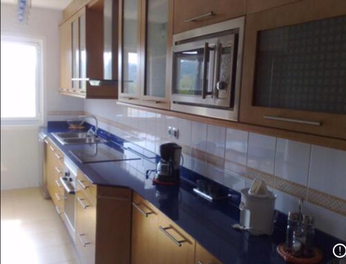 a kitchen with wooden cabinets and a blue counter top at A Coruña al lado de la playa in Bastiagueiro