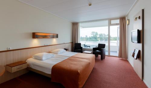 een hotelkamer met een bed, een bureau en een raam bij Hotel Princenhof in Earnewâld