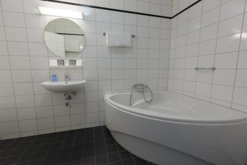 un bagno piastrellato bianco con vasca e lavandino di Hotel Princenhof a Earnewâld