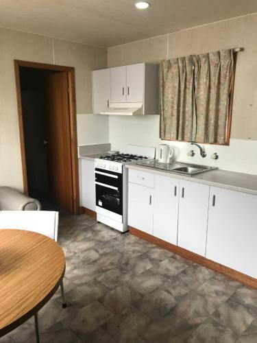 a kitchen with white cabinets and a sink and a table at Geelong Surfcoast Hwy Holiday Park in Mount Duneed