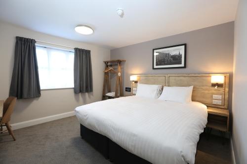 Schlafzimmer mit einem großen weißen Bett und einem Schreibtisch in der Unterkunft Tulip Queen, Spalding by Marston's Inns in Spalding