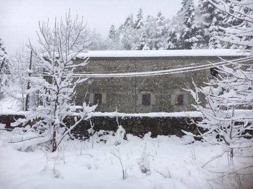 a snow covered building in a yard with trees at Maison en Ardeche in Usclades